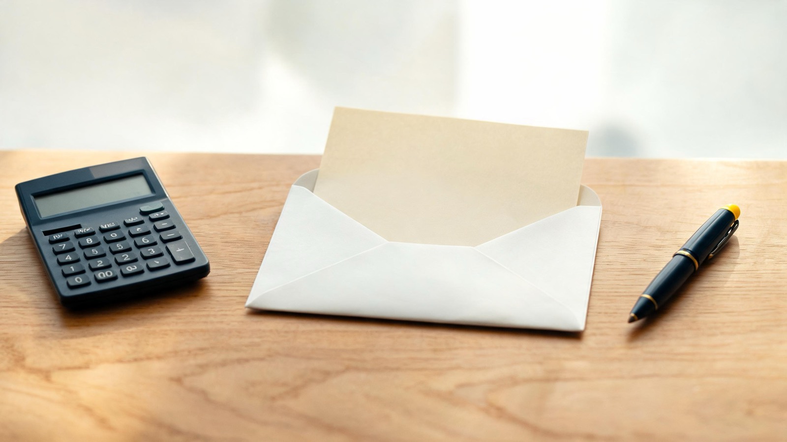 Brief wordt in een envelop gedaan naast een rekenmachine, ter illustratie van de huurverhogingsaanzegging
