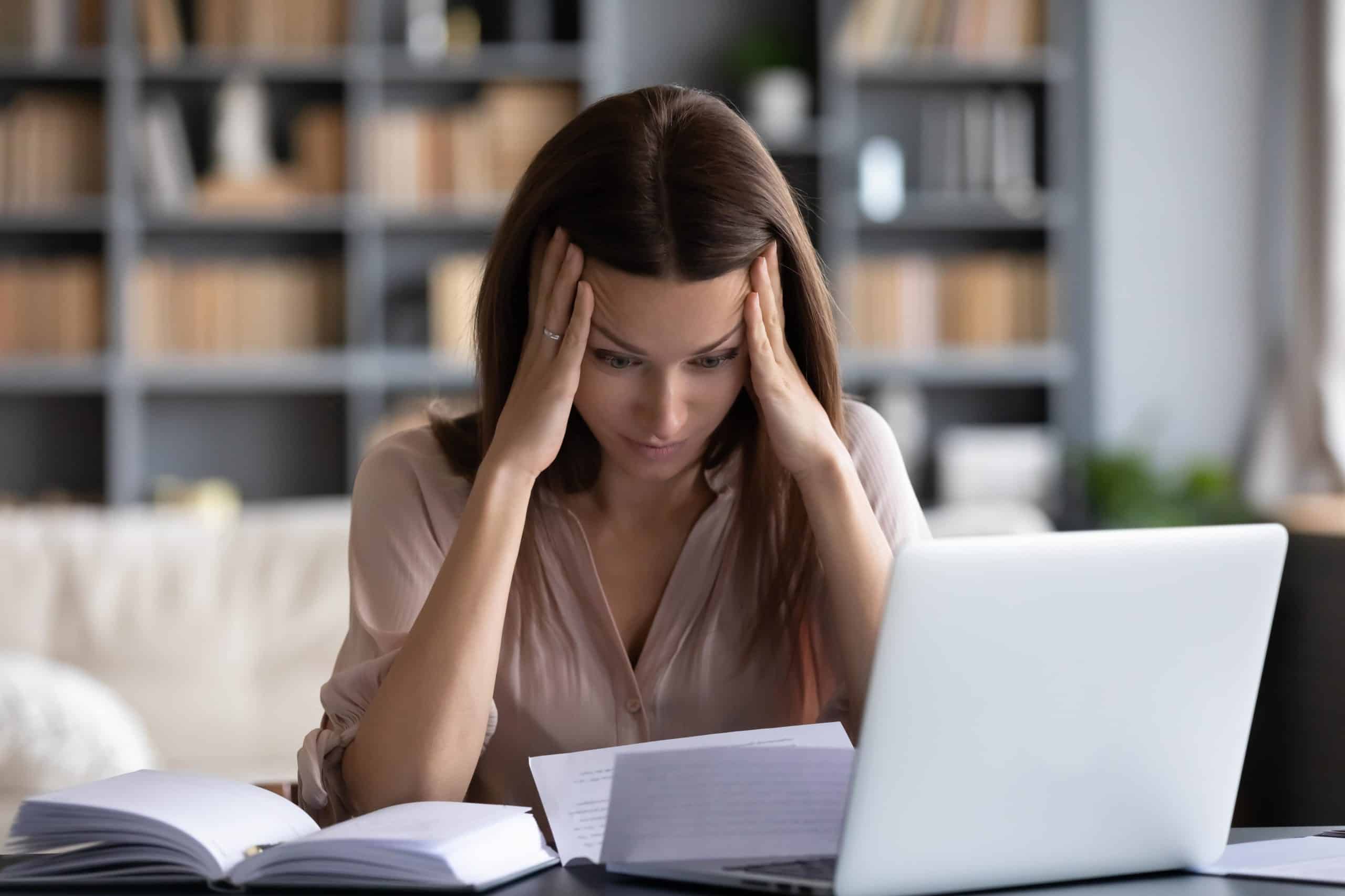 Verhuurder leest gespannen een brief achter haar laptop, symbool voor de gevolgen van beginnersfouten bij het verhuren
